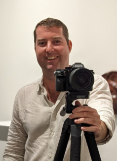 A sensual photograph of the poet, Sean F. Munro, gently standing behind a camera.