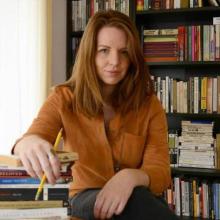 A picture of the writer Laura Paul sitting in front of a bookcase.